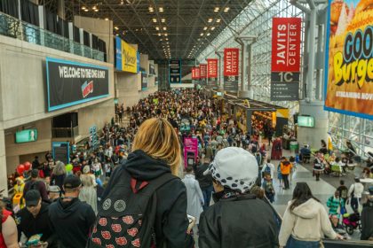 Público circula pelo Javits Center durante a New York Comic Con, com fãs usando fantasias de cosplay.